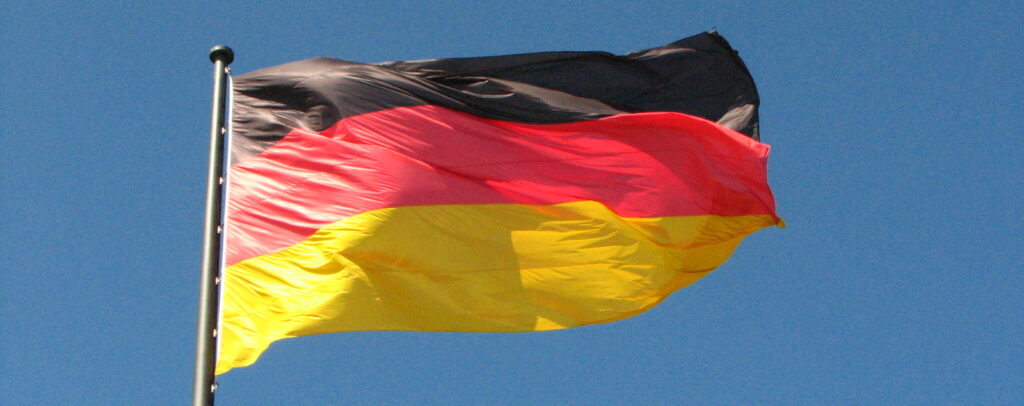 Vor blauem Himmel weht eine Flagge mit horizontalen Streifen in Schwarz-Rot-Gold.