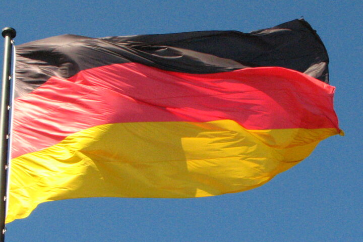 Vor blauem Himmel weht eine Flagge mit horizontalen Streifen in Schwarz-Rot-Gold.